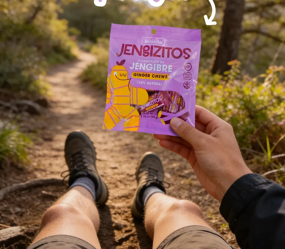 Bolsa lila de caramelos de jengibre Jengizitos en la mano, en un sendero de montaña